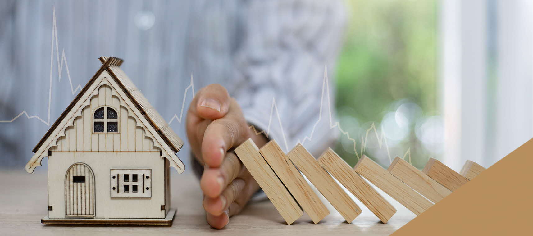 Image showing a hand blocking wooden blocks from falling onto a model house.