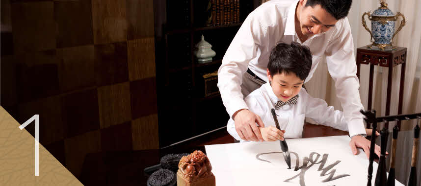 Father guiding his son’s control of a calligraphy brush to show that legacy planning starts from the heart.