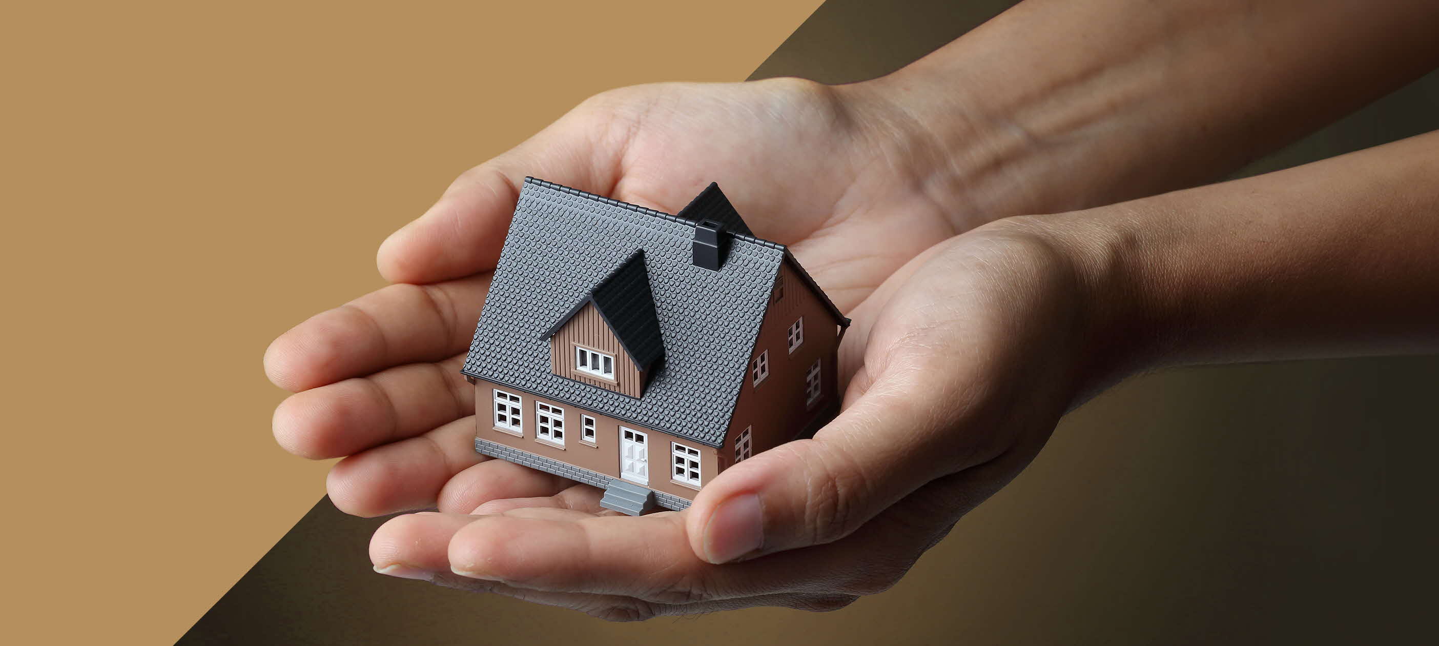 Two hands holding a toy model of a terrace house.